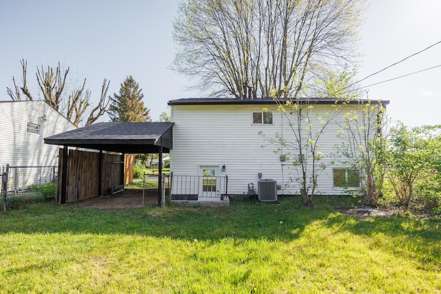 rear view of house with central AC, fence, a yard, and a carport