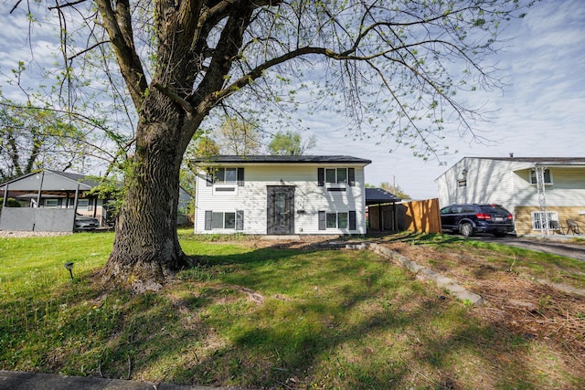 bi-level home with a front lawn and fence