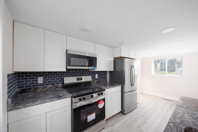 kitchen with white cabinets, stainless steel appliances, decorative backsplash, and light wood-style flooring
