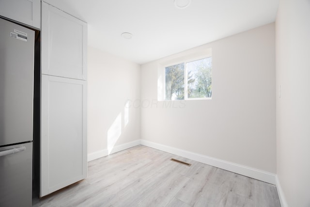 spare room featuring baseboards, light wood finished floors, and visible vents