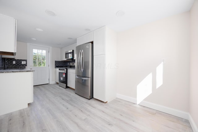 kitchen featuring light wood finished floors, backsplash, white cabinetry, and stainless steel appliances