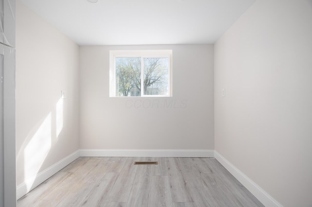 empty room featuring baseboards, light wood finished floors, and visible vents