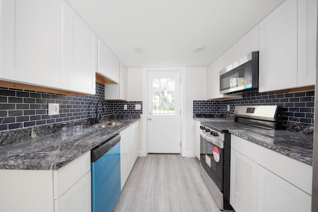 kitchen featuring white cabinets, appliances with stainless steel finishes, a sink, and light wood-type flooring