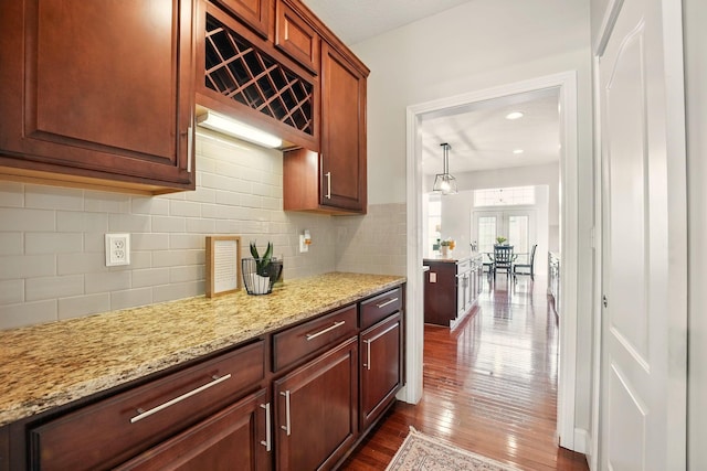 kitchen featuring light stone countertops, backsplash, and dark wood finished floors