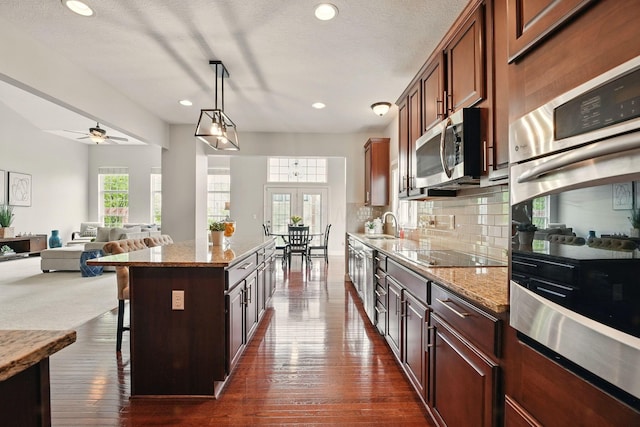 kitchen with a center island, light stone countertops, a breakfast bar, stainless steel appliances, and recessed lighting