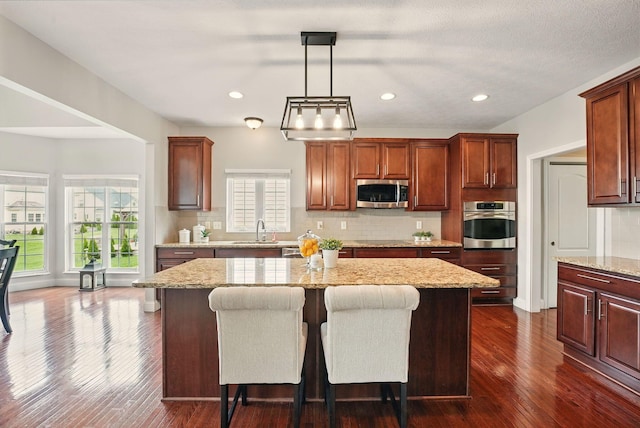 kitchen featuring a sink, decorative backsplash, appliances with stainless steel finishes, and a kitchen island