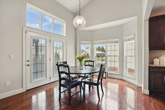 dining area featuring high vaulted ceiling, baseboards, dark wood-style flooring, and a notable chandelier