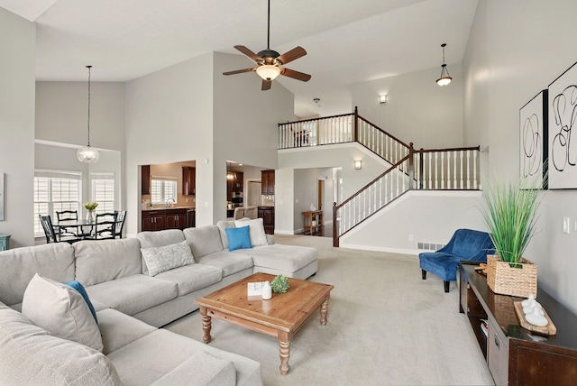 carpeted living room featuring ceiling fan, high vaulted ceiling, stairs, baseboards, and visible vents