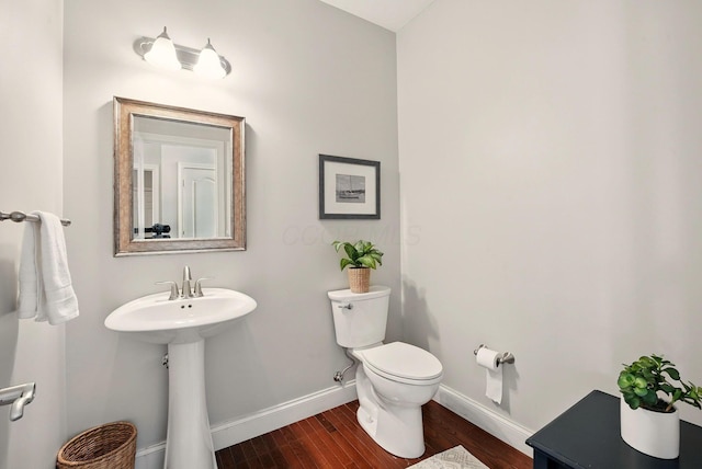 bathroom with toilet, baseboards, a sink, and wood finished floors