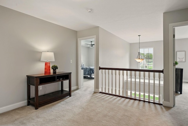 hallway with baseboards, carpet, and an upstairs landing