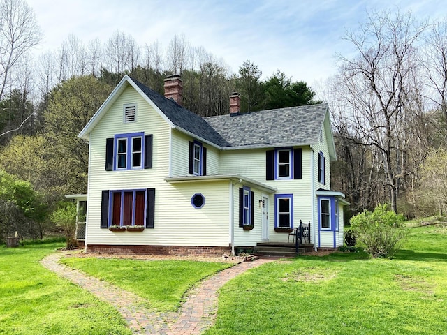 traditional home with roof with shingles, a chimney, and a front yard