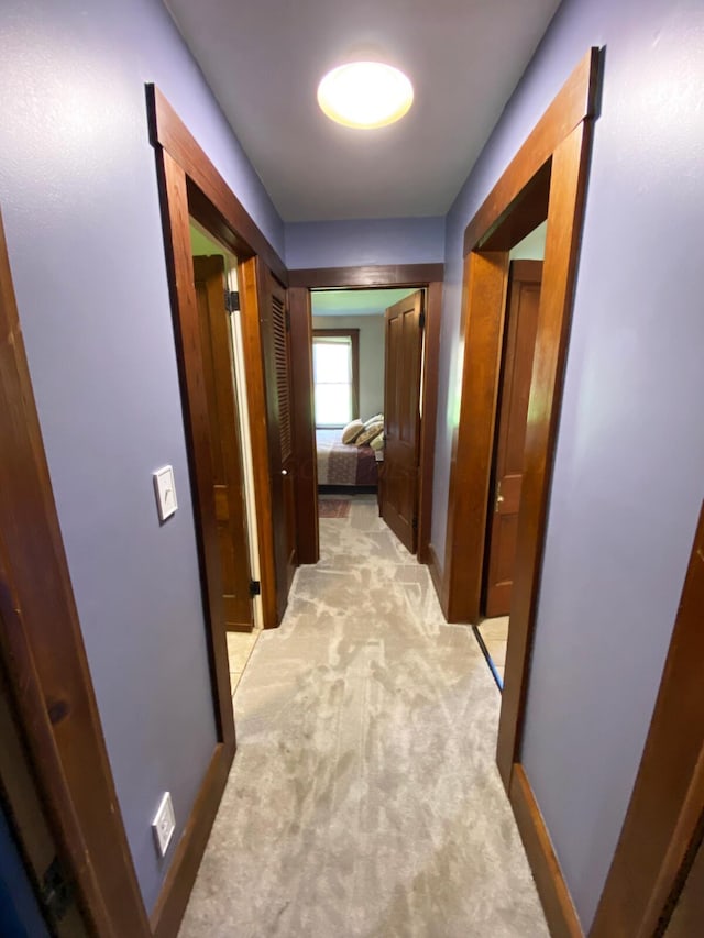 hall with baseboards and light colored carpet