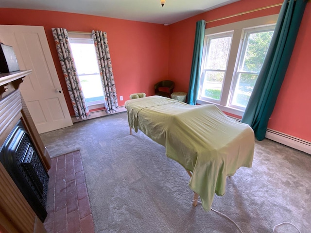 carpeted bedroom with a baseboard radiator, multiple windows, and a fireplace