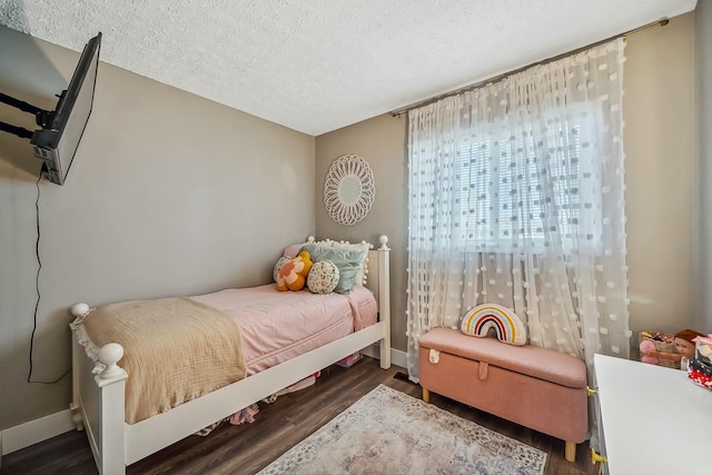 bedroom with a textured ceiling, baseboards, and wood finished floors