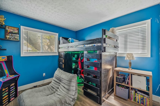 bedroom with baseboards, a textured ceiling, and wood finished floors