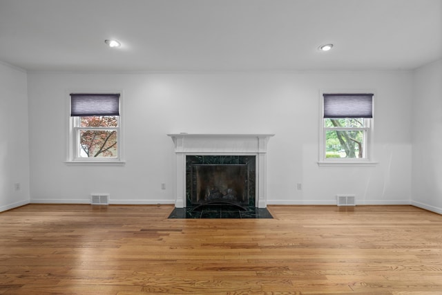 unfurnished living room with visible vents, plenty of natural light, and a fireplace