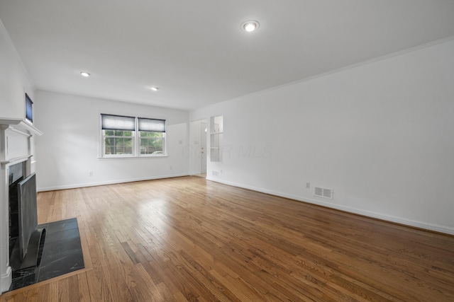 unfurnished living room featuring visible vents, a fireplace with flush hearth, wood finished floors, baseboards, and recessed lighting
