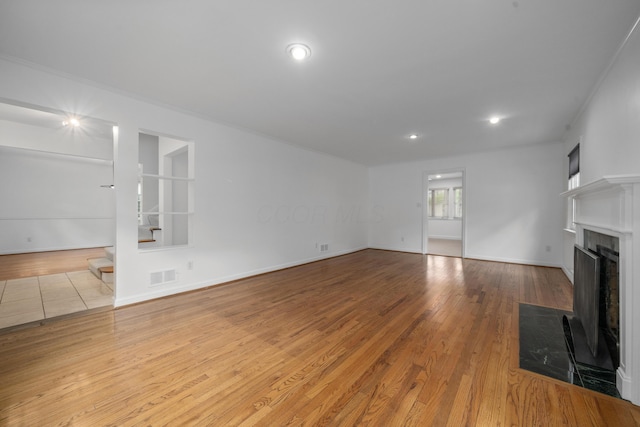 unfurnished living room with recessed lighting, baseboards, a fireplace with flush hearth, wood finished floors, and visible vents