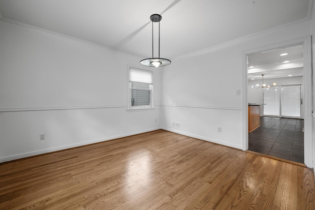 unfurnished dining area with visible vents, crown molding, wood finished floors, baseboards, and an inviting chandelier