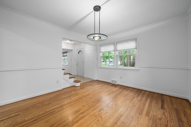 unfurnished dining area featuring crown molding, visible vents, a healthy amount of sunlight, and wood finished floors