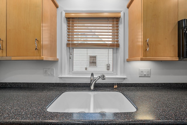 kitchen with a sink and dark stone counters