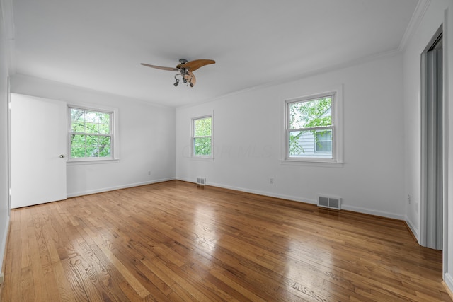 spare room with crown molding, ceiling fan, hardwood / wood-style flooring, and visible vents