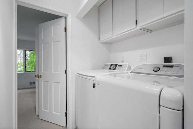 clothes washing area with cabinet space, visible vents, and washer and clothes dryer