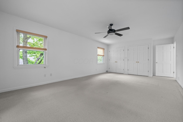 unfurnished bedroom featuring baseboards, two closets, and carpet floors