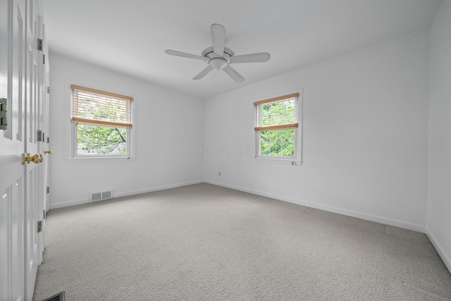 carpeted empty room with a ceiling fan, baseboards, and visible vents
