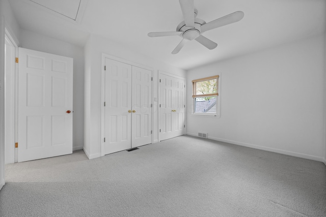 unfurnished bedroom with visible vents, carpet flooring, baseboards, and two closets