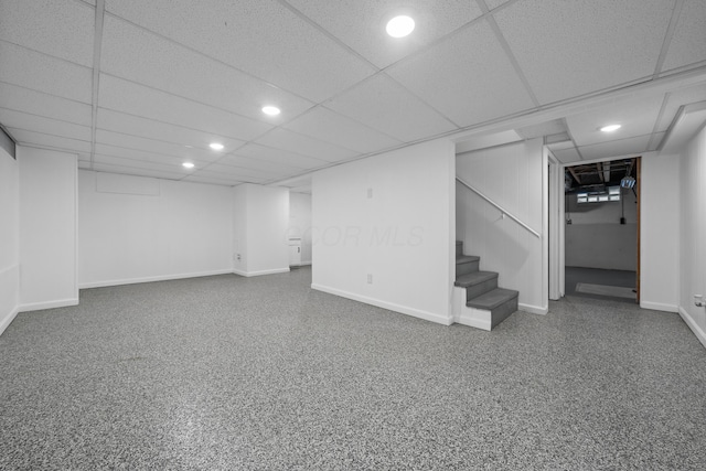 finished basement with baseboards, recessed lighting, stairs, and a drop ceiling