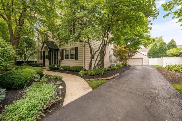 view of front facade with an outdoor structure, a garage, aphalt driveway, fence, and cooling unit