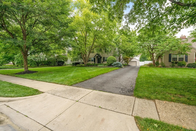 view of property hidden behind natural elements featuring a garage and a front yard