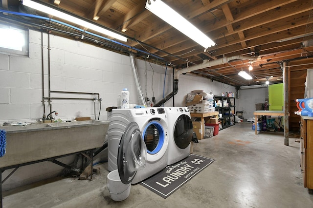 unfinished basement with washer and clothes dryer, a sink, and concrete block wall