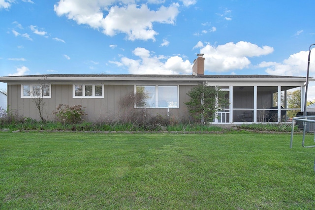 rear view of house with a sunroom, a chimney, a yard, and central AC