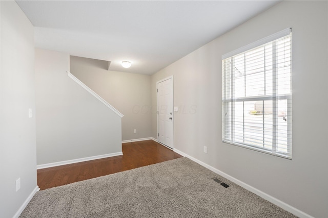 foyer with carpet flooring, baseboards, visible vents, and stairs