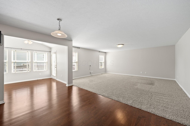 unfurnished living room with baseboards, dark wood finished floors, and a textured ceiling