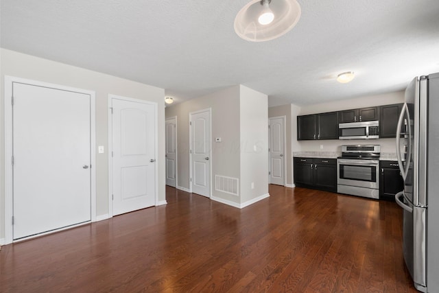 kitchen featuring light countertops, stainless steel appliances, baseboards, dark wood-type flooring, and visible vents