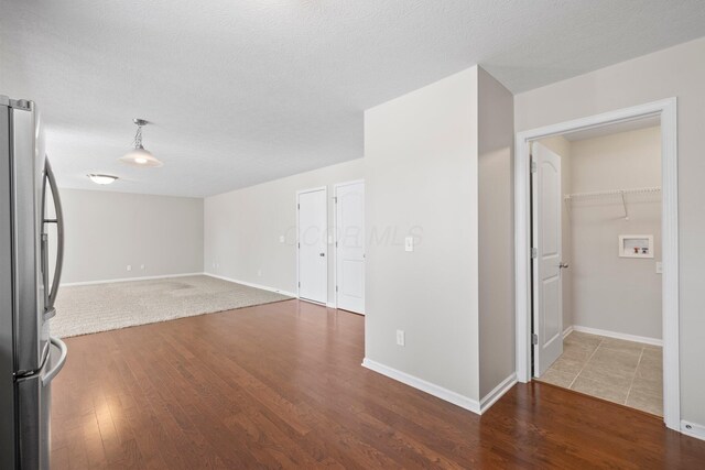 unfurnished living room with a textured ceiling, baseboards, and wood finished floors
