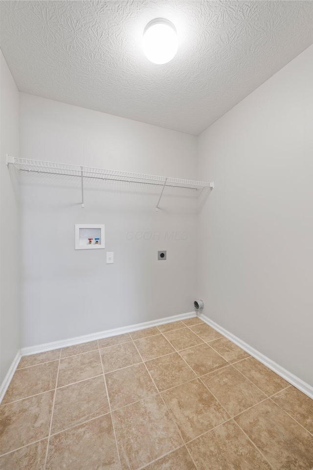 clothes washing area with laundry area, baseboards, hookup for a washing machine, a textured ceiling, and hookup for an electric dryer