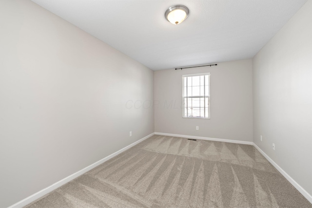 empty room featuring baseboards, light colored carpet, and visible vents