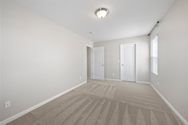 spare room with baseboards and light carpet