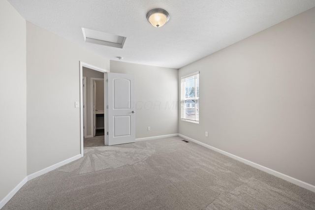 empty room with baseboards, visible vents, light carpet, and attic access