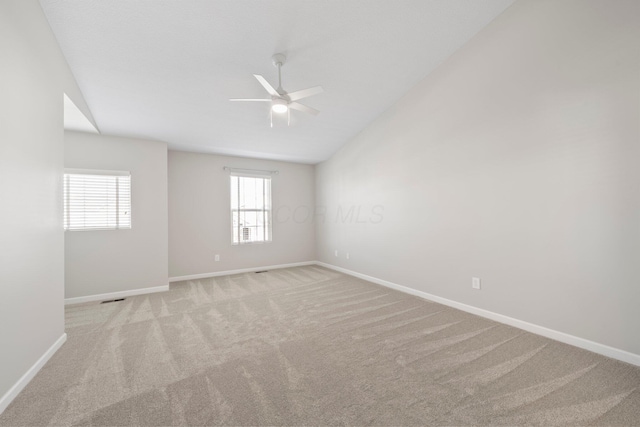 unfurnished room with vaulted ceiling, baseboards, a ceiling fan, and light colored carpet