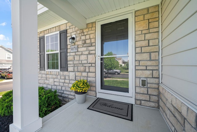 entrance to property featuring covered porch and stone siding