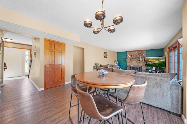 dining area with baseboards, a notable chandelier, wood finished floors, and a fireplace
