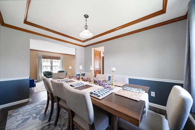 dining room with dark wood-style flooring, baseboards, ornamental molding, and a raised ceiling