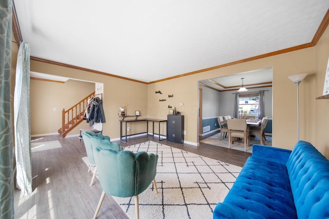 living area featuring visible vents, ornamental molding, wood finished floors, baseboards, and stairway