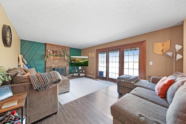 living room featuring a brick fireplace, a textured ceiling, french doors, and wood finished floors