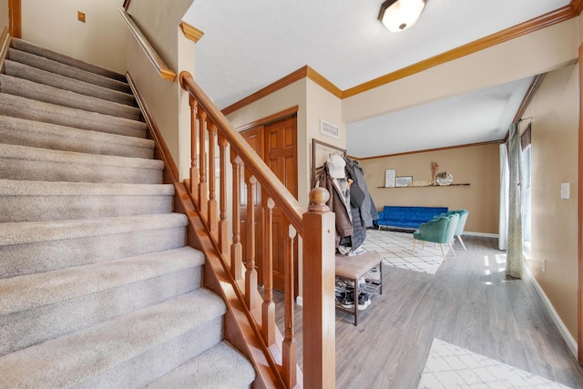 stairs with baseboards, ornamental molding, and wood finished floors